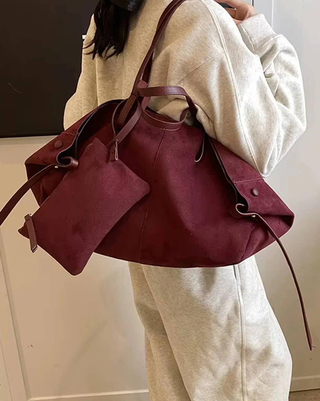 Woman carrying large dark brown suede tote bag with matching pouch