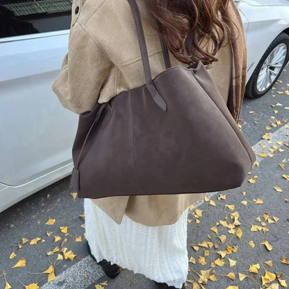 Woman holding large brown vegan suede handbag in retro style on autumn street