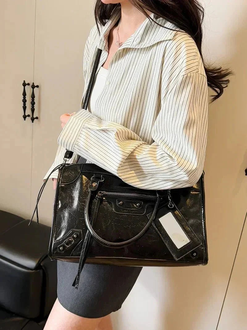 Woman holding a stylish black minimalist handbag with spacious interior and zipper pocket