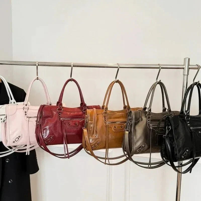 Row of stylish handbags in pink, red, brown, olive, and black with minimalist design