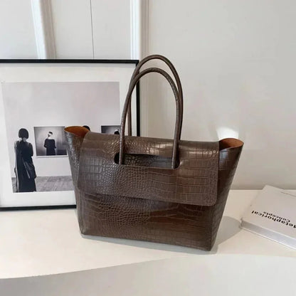 Dark brown crocodile pattern large tote handbag for women on white table
