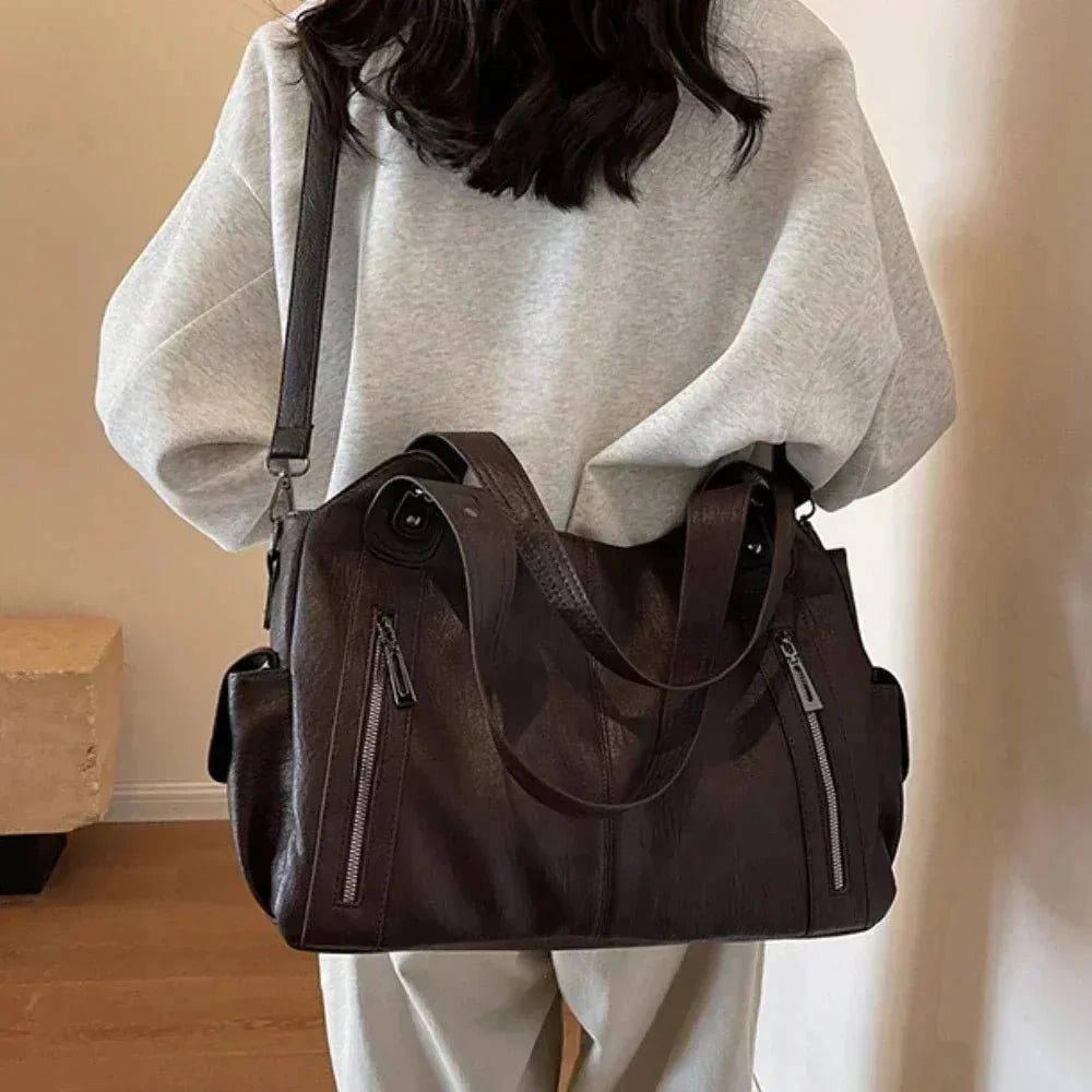 Woman wearing a spacious black shoulder bag with zip pockets and adjustable strap